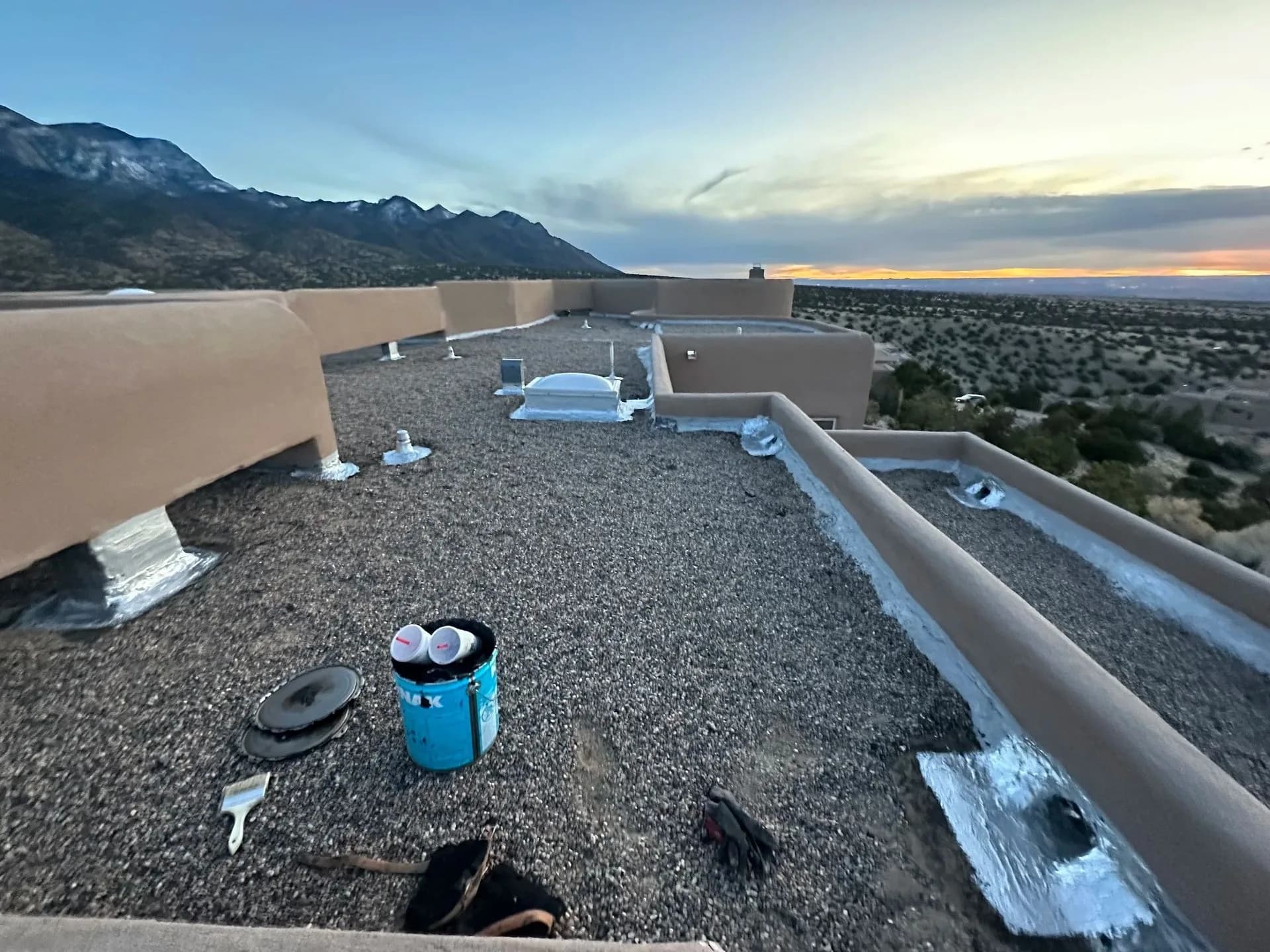 Gravel roof coating application at sunset